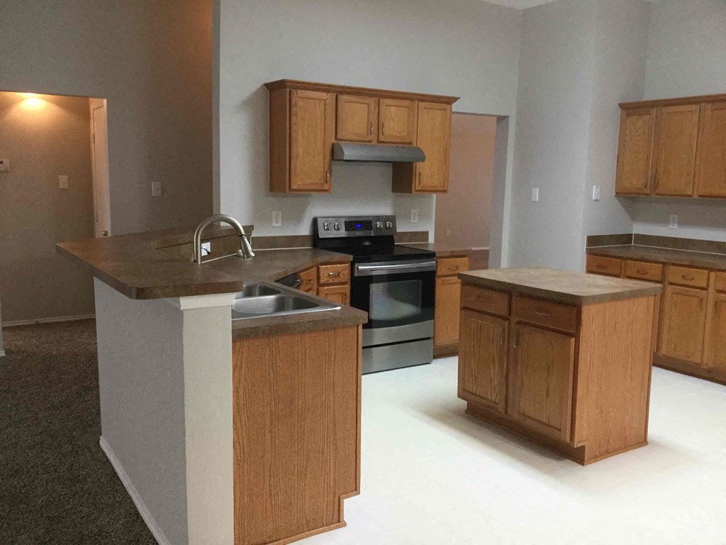 an empty kitchen with wooden cabinets and a sink