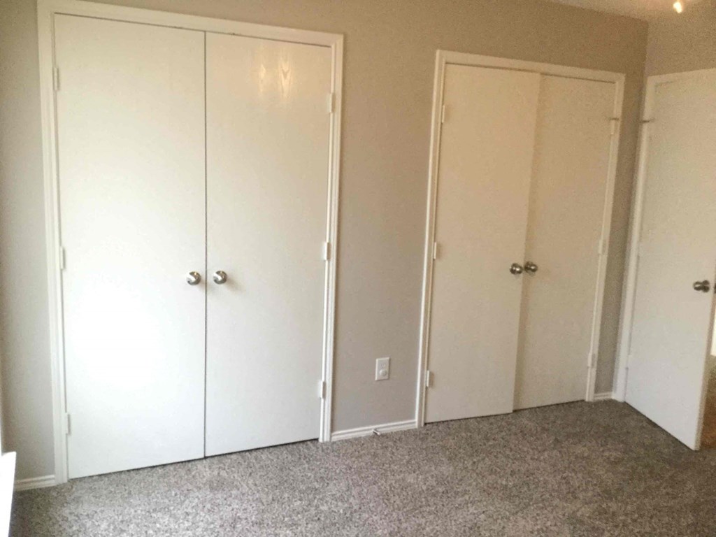 a bedroom with three closets and a carpeted floor