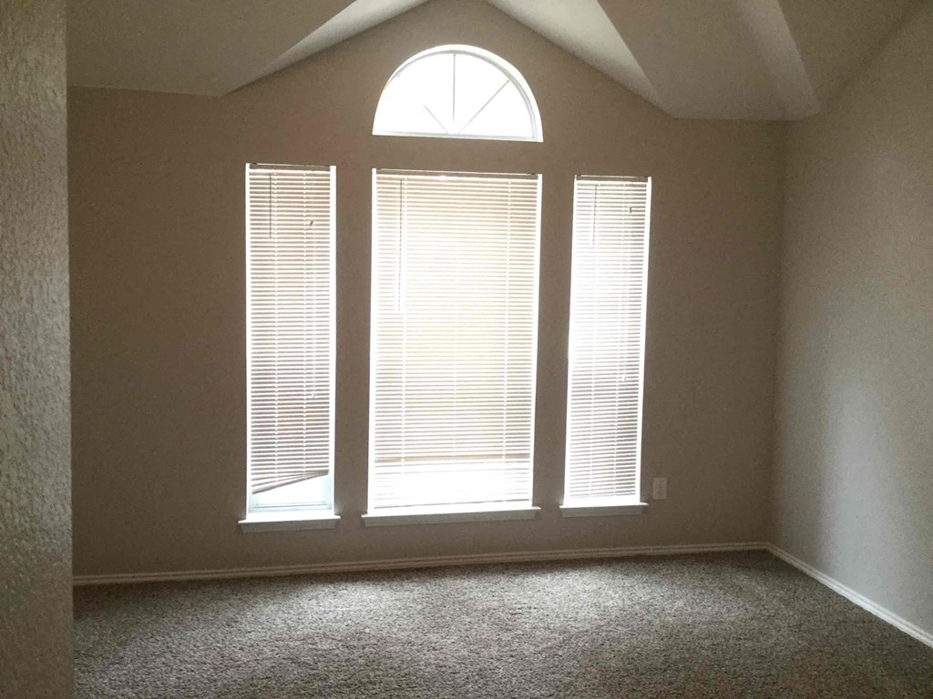 an empty living room with three large windows
