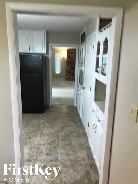 A kitchen with white cabinets and a black fridge.