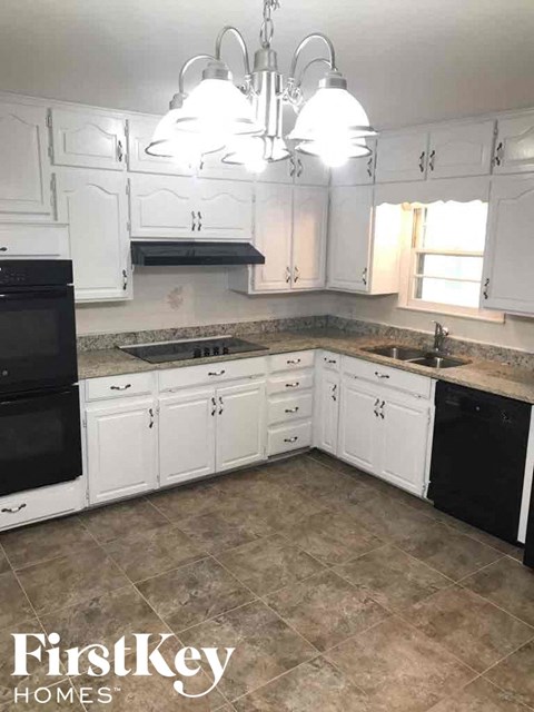A kitchen with white cabinets and a black dishwasher.