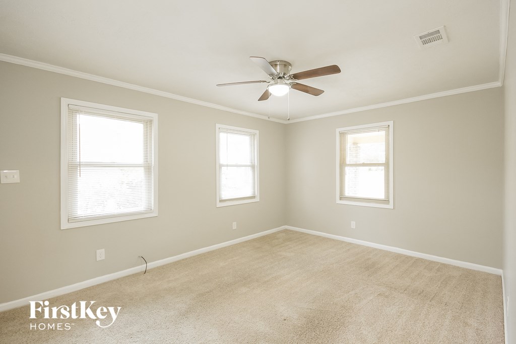 an empty room with a ceiling fan and two windows