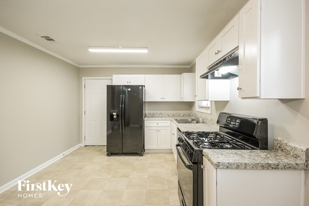 a kitchen with white cabinets and a black refrigerator