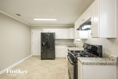 a kitchen with white cabinets and a black refrigerator