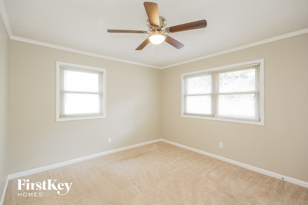 a bedroom with a ceiling fan and two windows