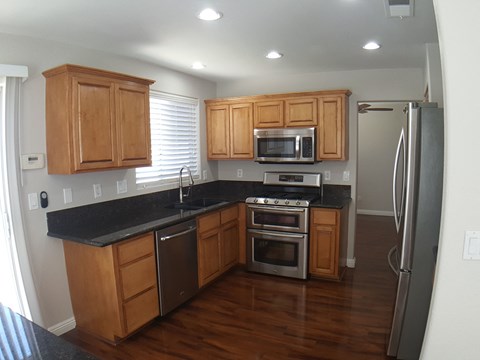 A kitchen with wooden cabinets and black countertops.