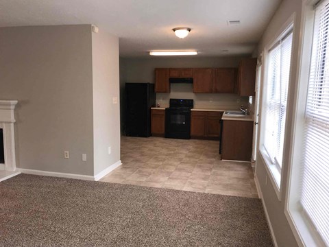 A kitchen area with a black refrigerator and wooden cabinets.
