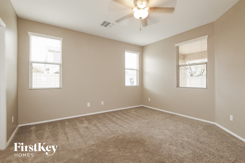 an empty room with a ceiling fan and two windows