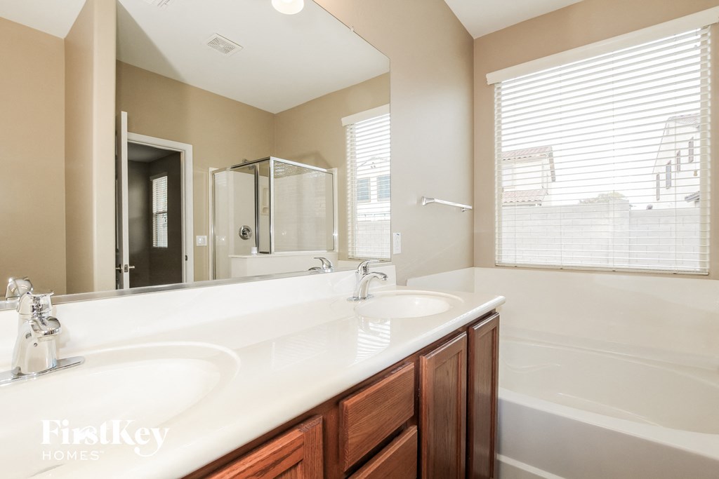 a bathroom with two sinks and a tub and a large mirror