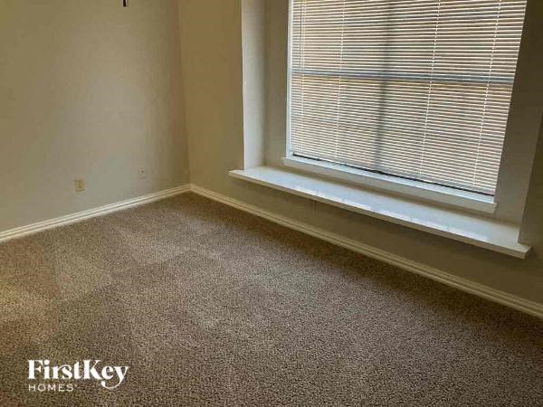 A room with a carpeted floor and a window with blinds.