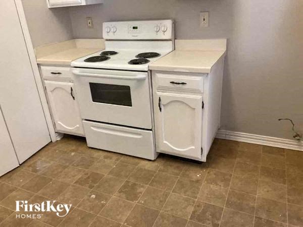 A white kitchen with a stove, oven, and cabinet.