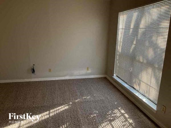 A room with a carpet floor and a window with blinds.