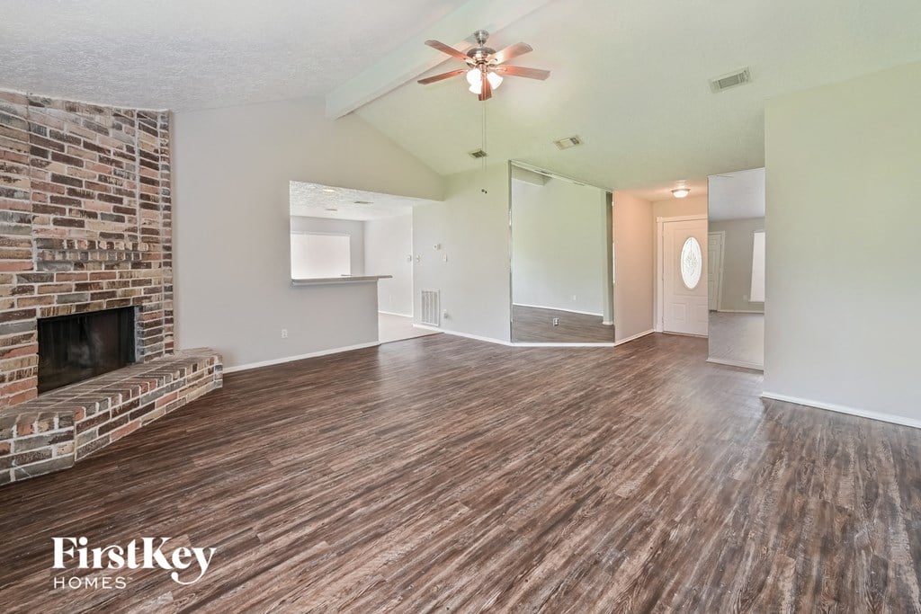 an empty living room with a fireplace and a ceiling fan