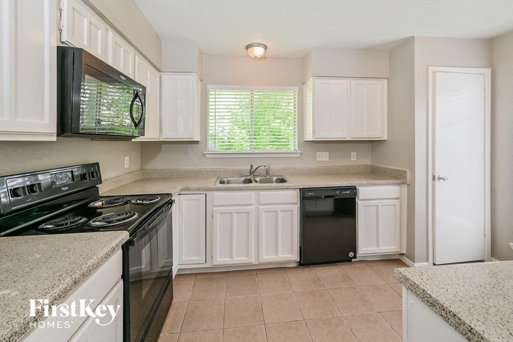 a kitchen with white cabinets and black appliances