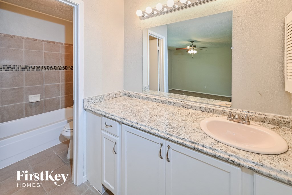 a bathroom with white cabinets and a sink and a mirror