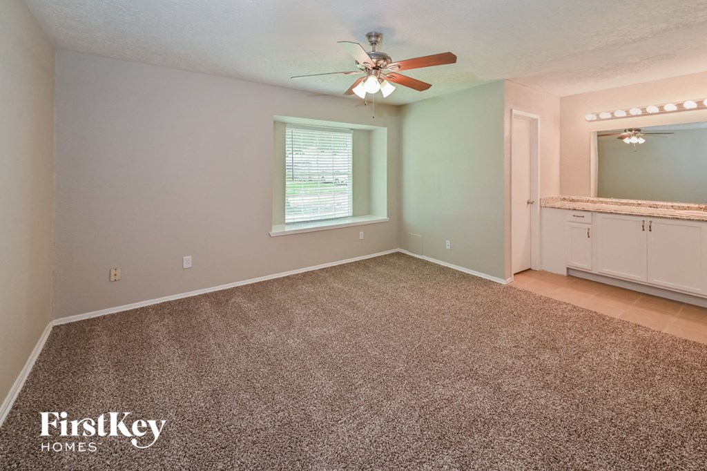 the master bedroom has a carpeted floor and a ceiling fan