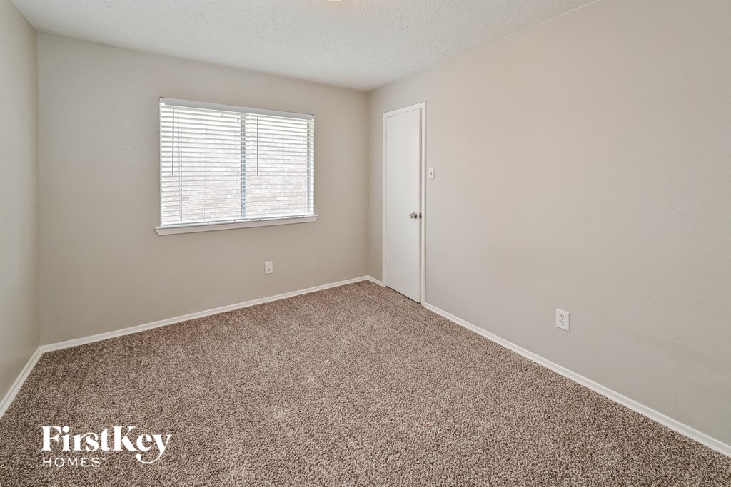 the spacious bedroom with carpeted flooring and a window