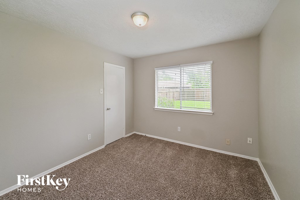 a bedroom with carpet and a window and a door