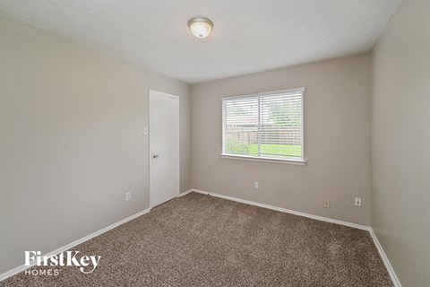 a bedroom with carpet and a window and a door