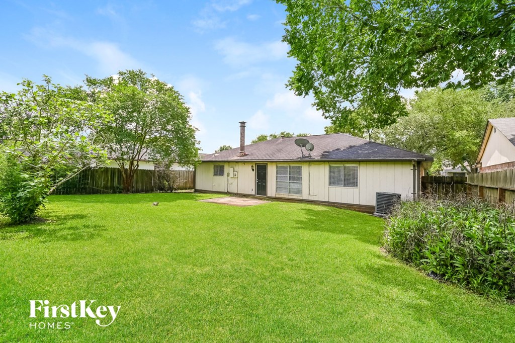 a backyard with a white house and a grassy yard