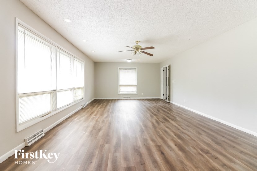 an empty living room with wood floors and a ceiling fan