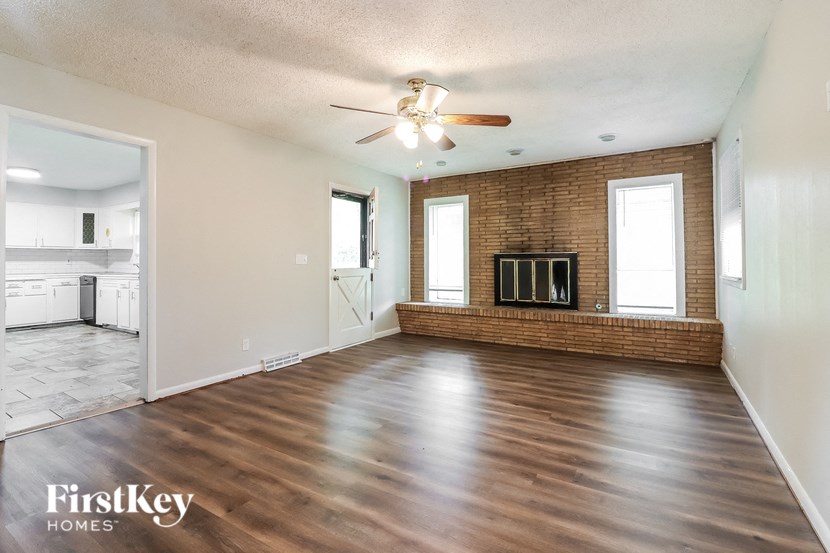 an empty living room with a fireplace and a ceiling fan
