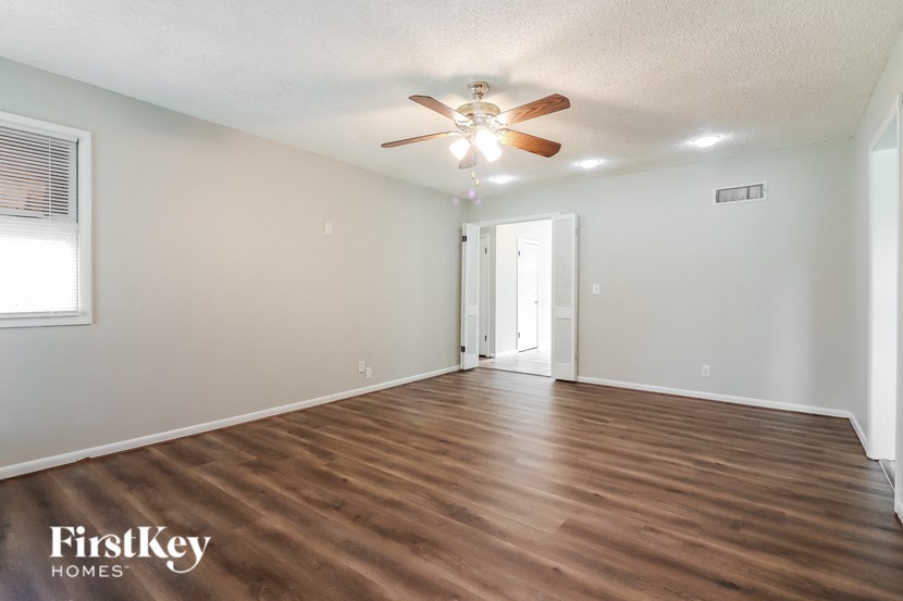 an empty living room with a ceiling fan and wood floors