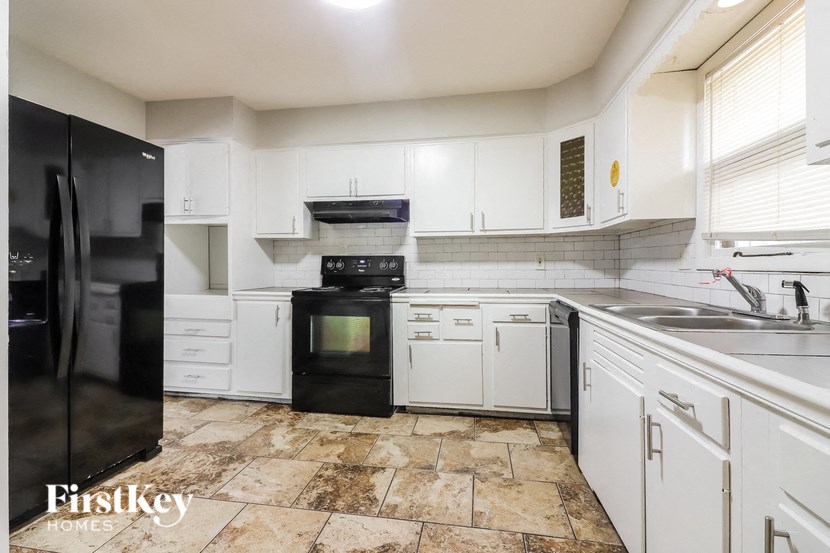 a renovated kitchen with white cabinets and black appliances
