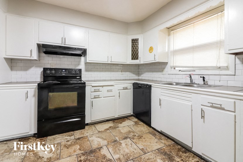 a white kitchen with black appliances and white cabinets