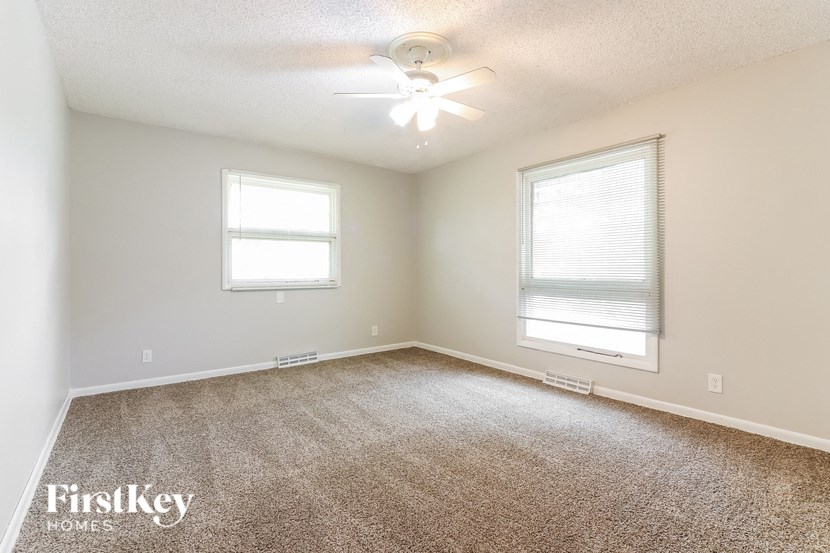 an empty living room with a ceiling fan and a window