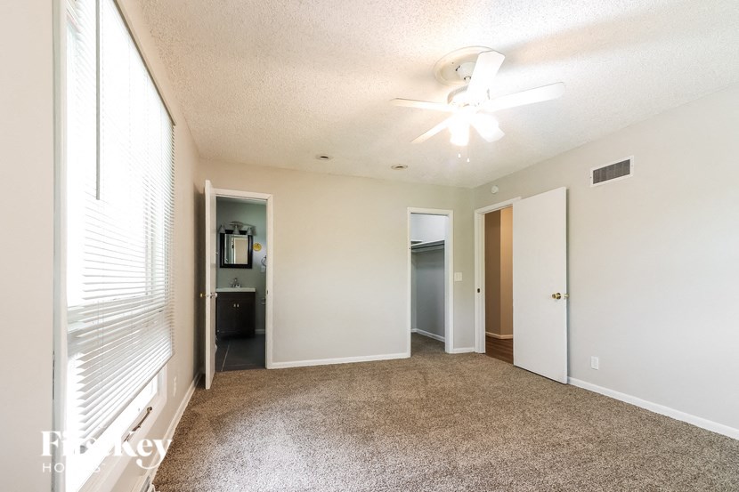 an empty living room with a large window and a ceiling fan