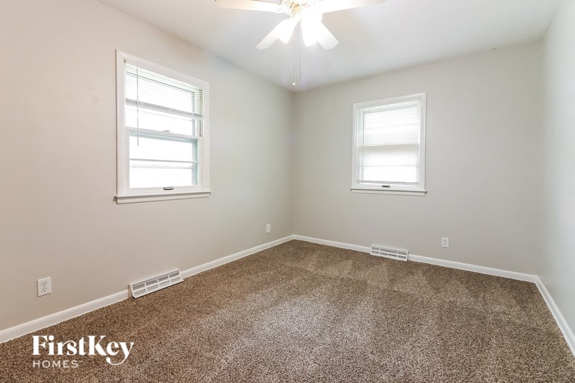 a bedroom with a carpeted floor and two windows
