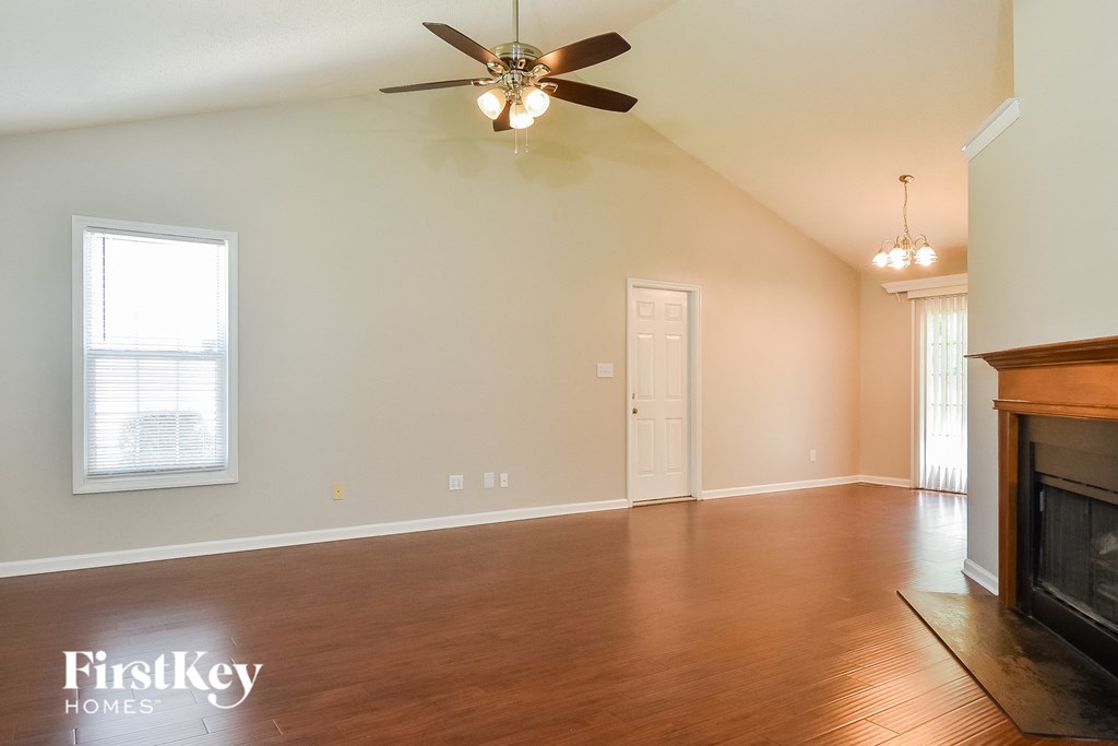 an empty living room with a ceiling fan and a fireplace
