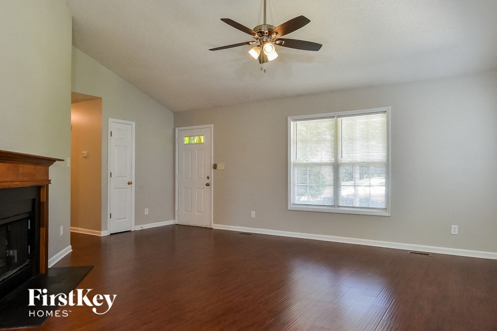 an empty living room with wood floors and a ceiling fan