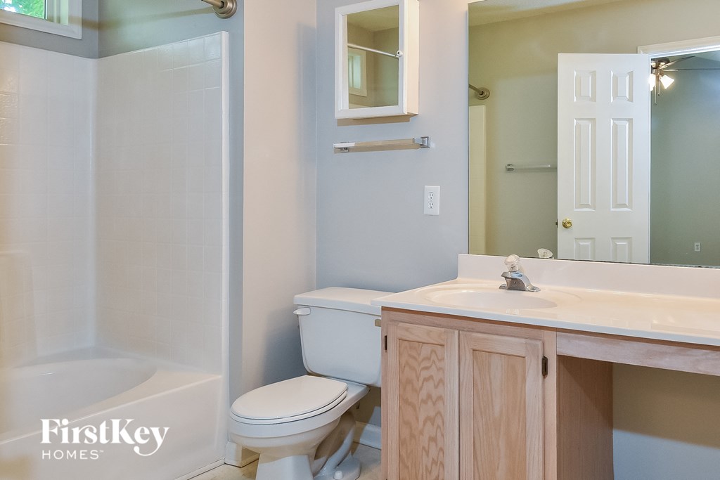 a bathroom with a toilet sink and shower and a mirror
