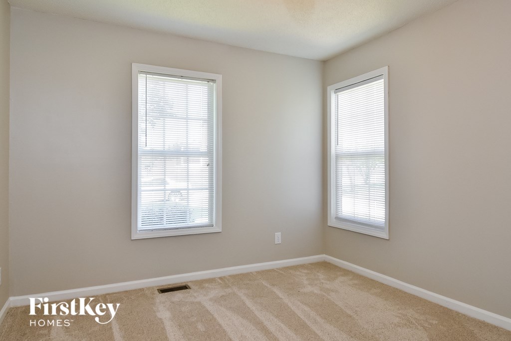 a bedroom with two windows and a carpeted floor
