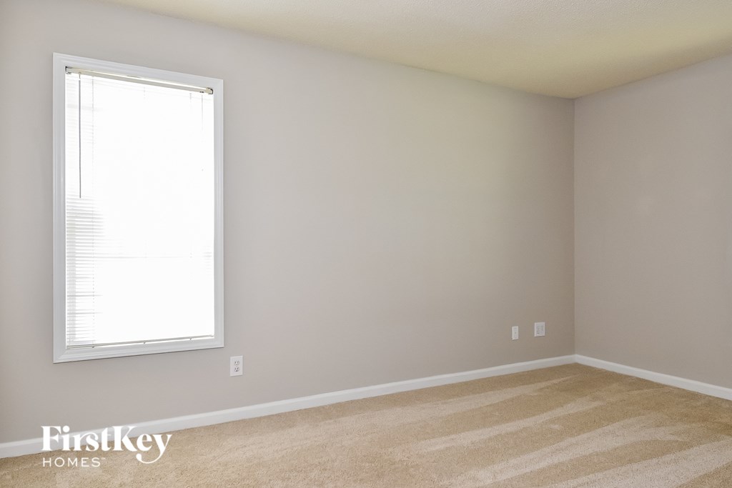 a bedroom with a window and a carpeted floor
