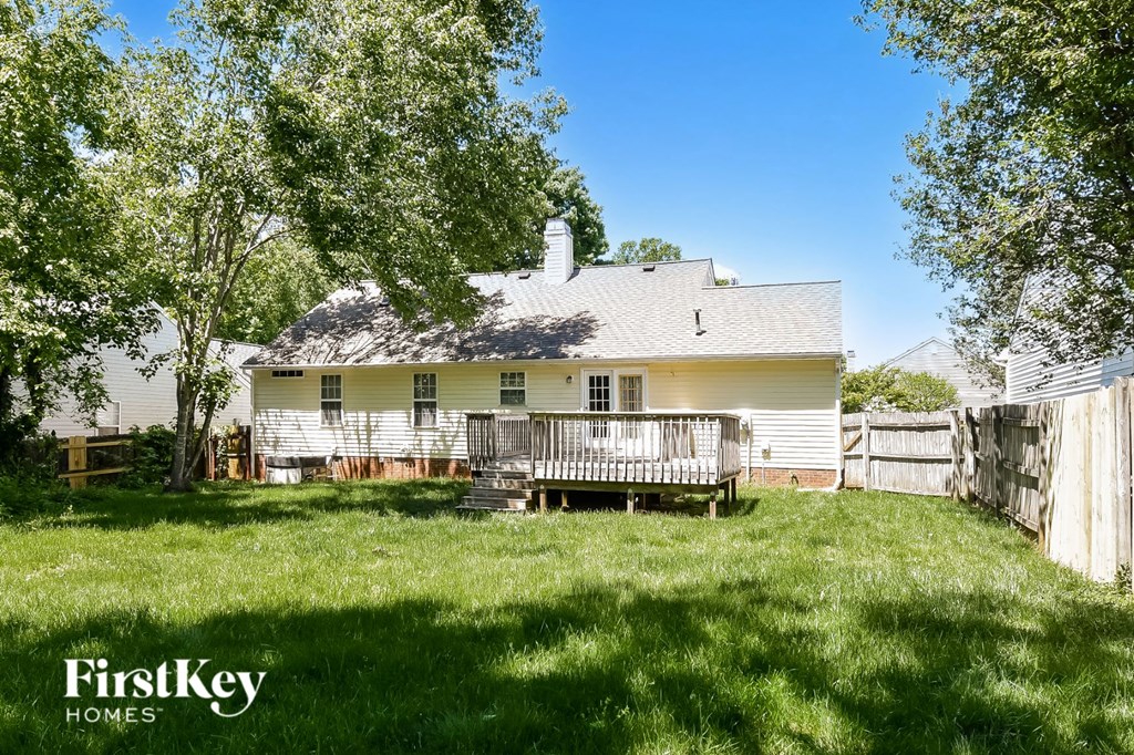 a backyard with a white house and a wooden fence