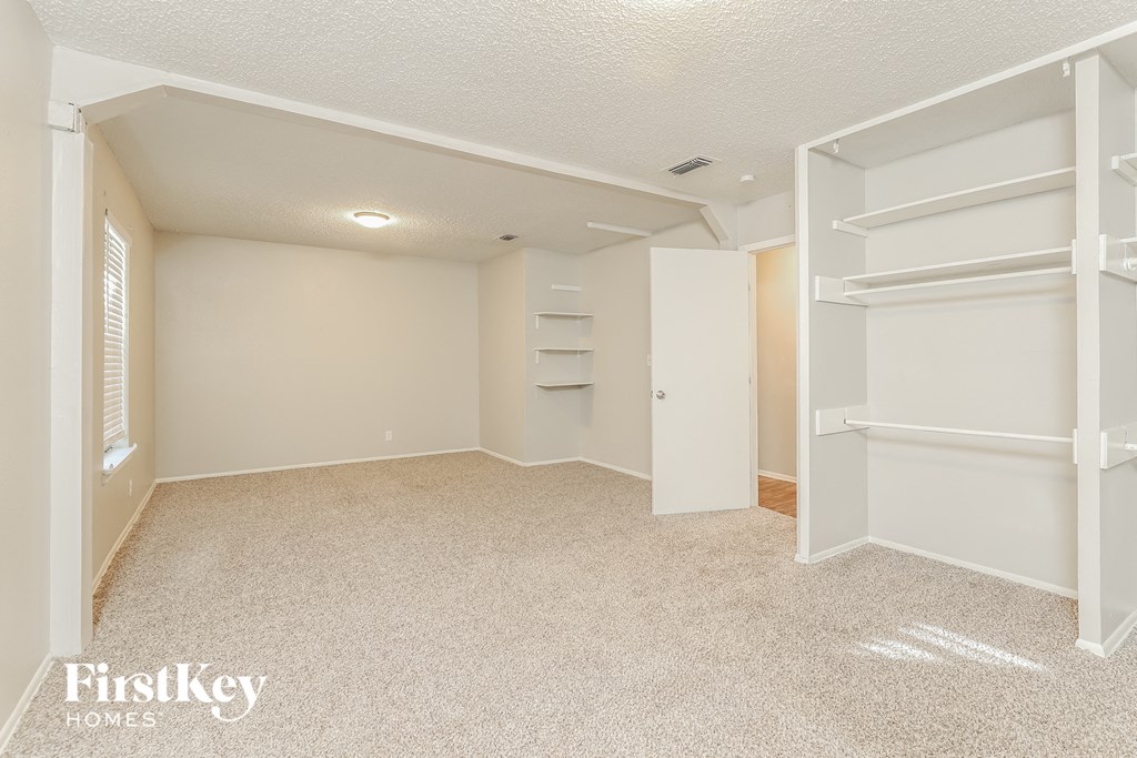 an empty bedroom with a closet and white shelves