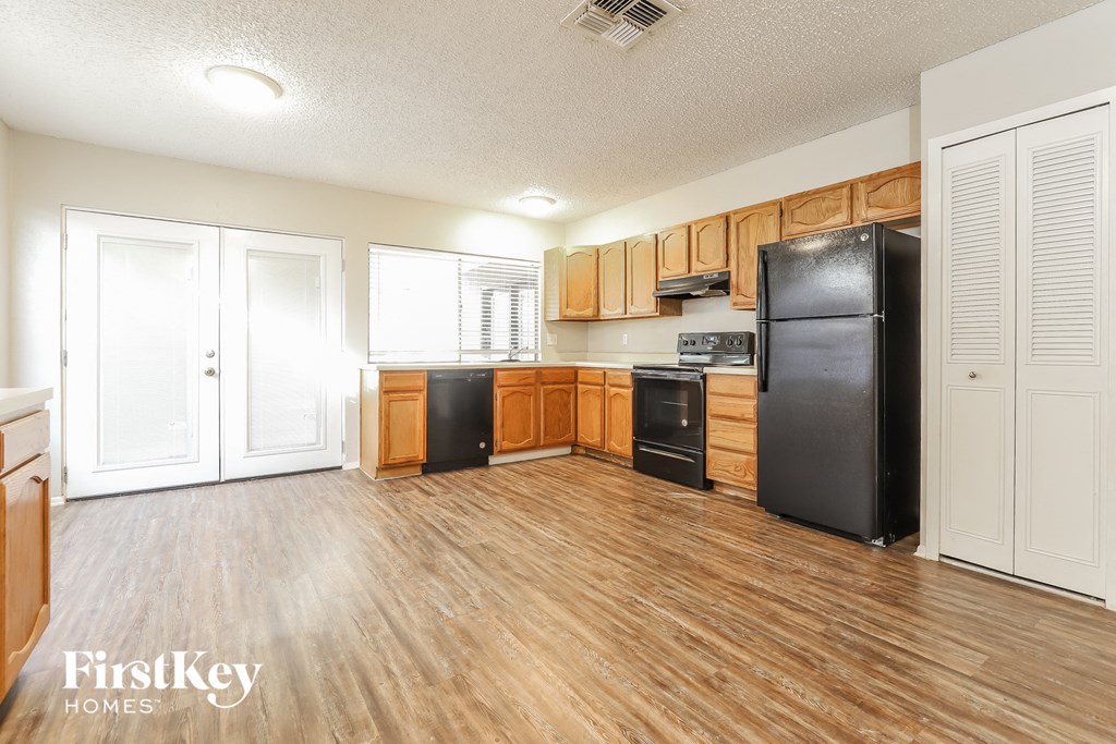a kitchen with wood flooring and a black refrigerator