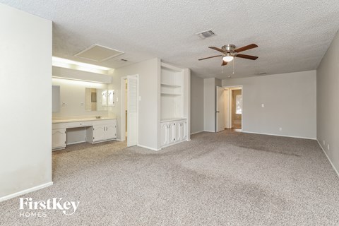 a living room with carpet and a ceiling fan