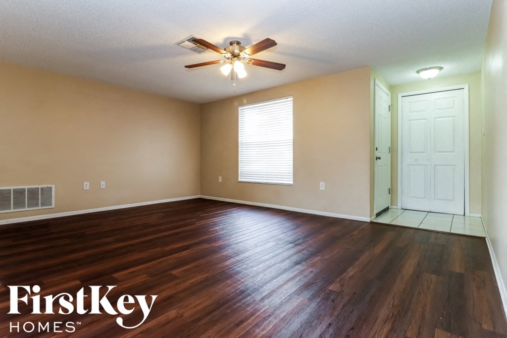 an empty living room with hardwood flooring and a ceiling fan
