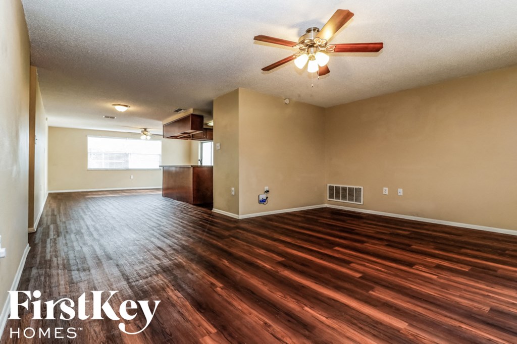 an empty living room with wood flooring and a ceiling fan