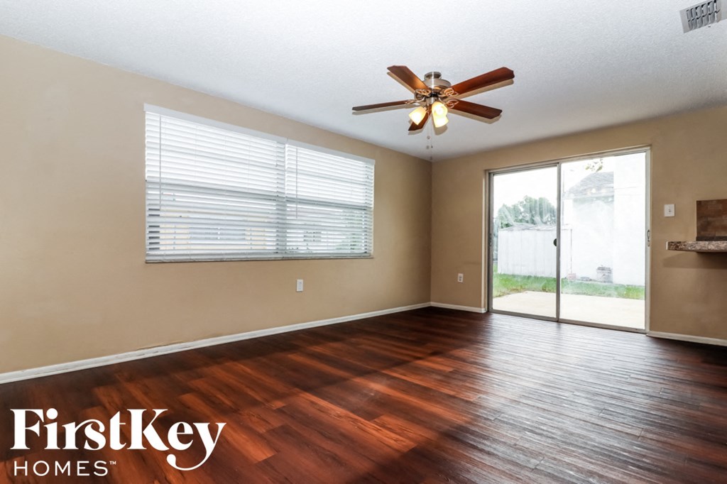 an empty living room with a ceiling fan and a sliding glass door