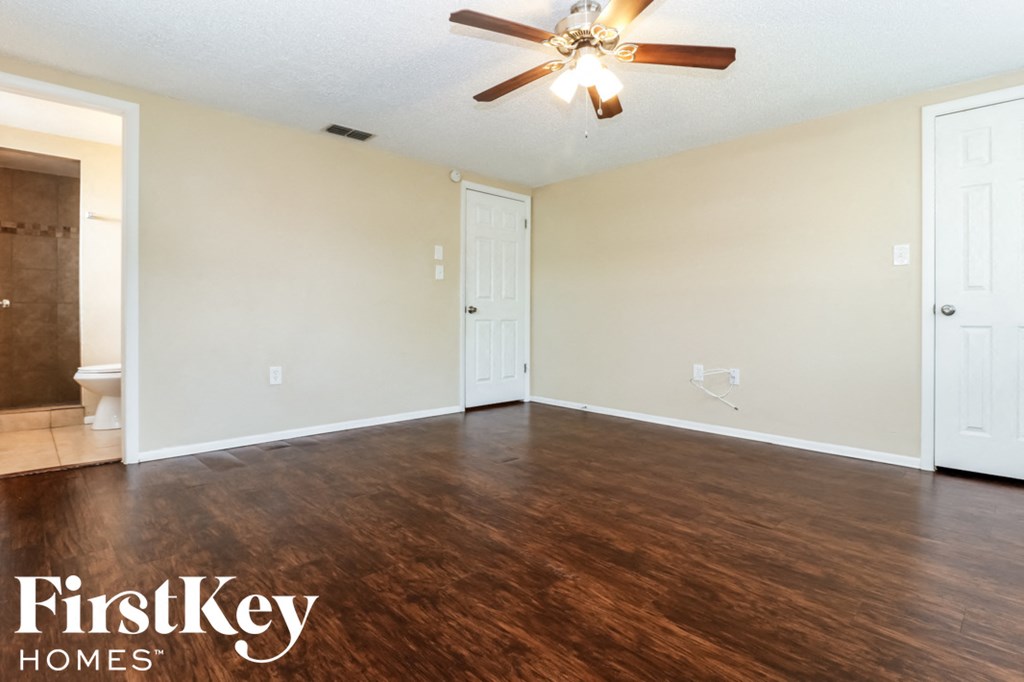 an empty living room with wood flooring and a ceiling fan