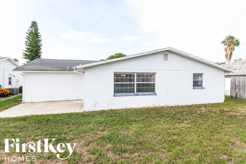 a small white house with a yard and a driveway