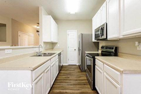 A kitchen with white cabinets and a black refrigerator.