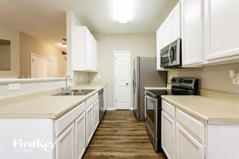 A kitchen with white cabinets and appliances.