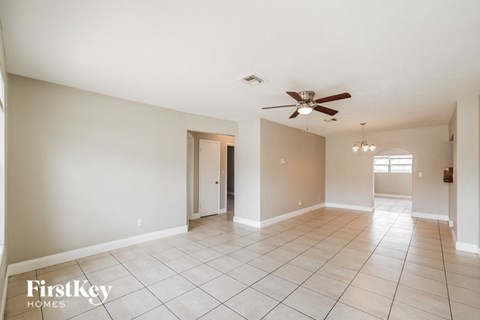 a spacious living room with tile flooring and a ceiling fan