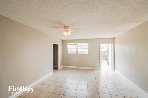 an empty living room with a ceiling fan and tiled floors